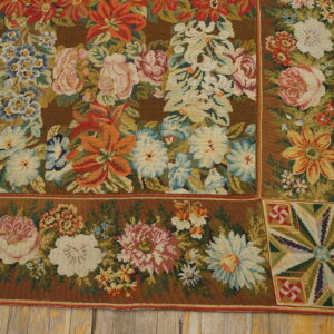Brown low-pile rug with a detailed border and multicolor floral pattern resting on distressed yellow wood planks.