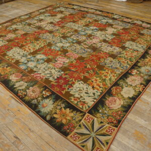 Flatweave rug with a dense multi-colored floral pattern and ornate border on distressed light wood flooring.