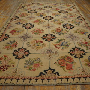 Large multicolored floral rug featuring a cream ground and black trellis pattern lays on wide plank wood flooring.