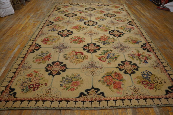 Large multicolored floral rug featuring a cream ground and black trellis pattern lays on wide plank wood flooring.