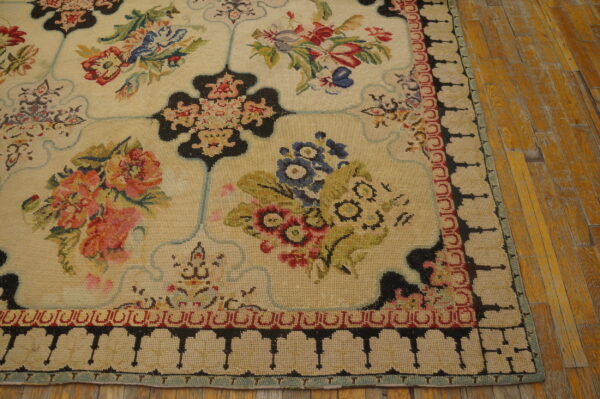 Low-pile cream rug with colorful floral panels and a black and red geometric border on wood flooring.