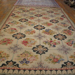 Cream floral rug featuring pink, blue, green, and dark navy motifs displayed on hardwood flooring.