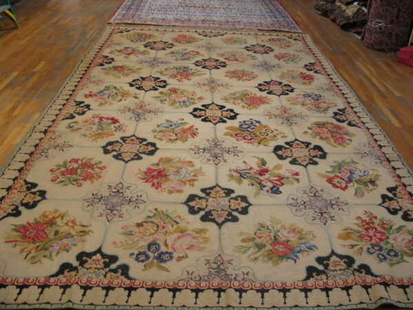Cream floral rug featuring pink, blue, green, and dark navy motifs displayed on hardwood flooring.
