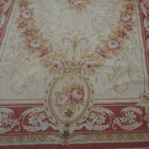 Low-pile floral rug featuring pink and tan roses on a cream ground with deep rose ornamental borders.