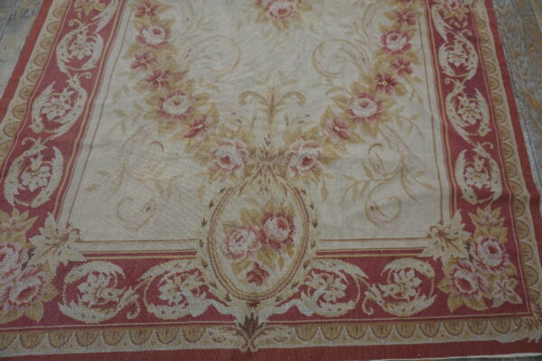 Low-pile floral rug featuring pink and tan roses on a cream ground with deep rose ornamental borders.
