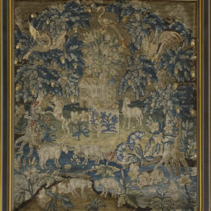 Framed, low-pile tapestry in blue, tan, and gold depicting a detailed forest scene with a house and various animals.