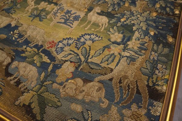 Muted blue, green, and beige framed tapestry textile with a detailed animal and floral scene design.
