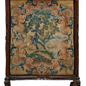 Needlepoint tapestry depicting a central scene framed by blue and tan scrolls, mounted in a carved wood screen.