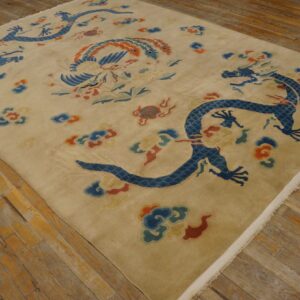 Beige rug featuring large blue dragon and phoenix motifs lying on distressed wooden flooring.