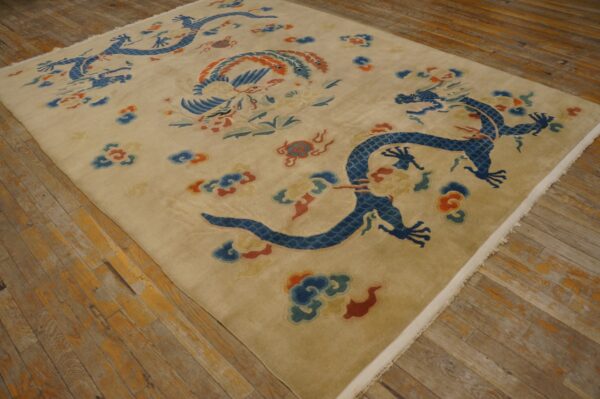 Beige rug featuring large blue dragon and phoenix motifs lying on distressed wooden flooring.