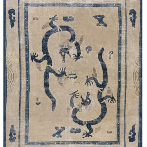Low pile beige rug featuring two intertwined dark blue dragon figures and detailed ornamental borders.