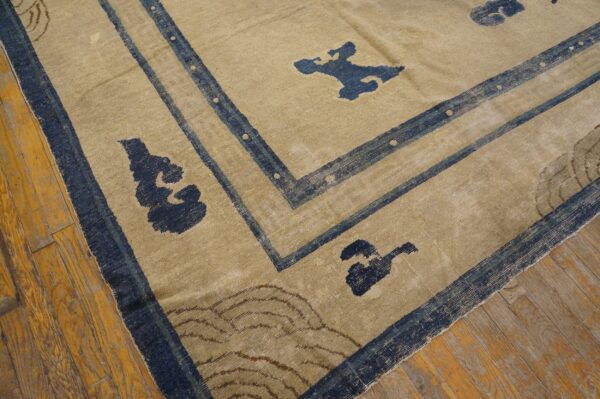 A distressed tan and blue low-pile rug with abstract patterns rests on worn wooden planks.