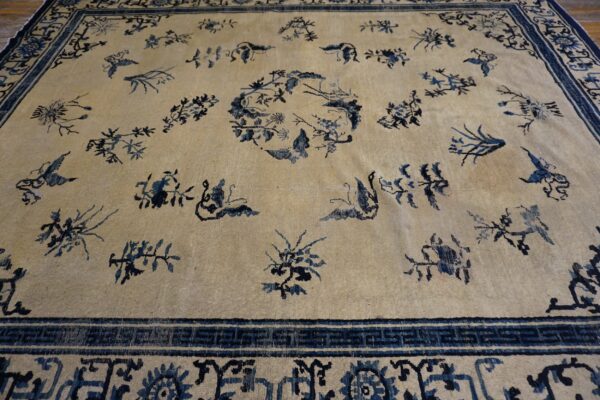 Cream low-pile rug featuring scattered dark blue floral motifs, a central medallion, and an elaborate border.