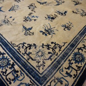 Light beige rug featuring scattered blue floral motifs and a detailed blue border, set on wood flooring.