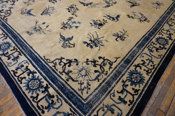 Light beige rug featuring scattered blue floral motifs and a detailed blue border, set on wood flooring.