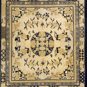 Cream rug featuring dark blue and gold stylized motifs, geometric borders, and a central round medallion design.