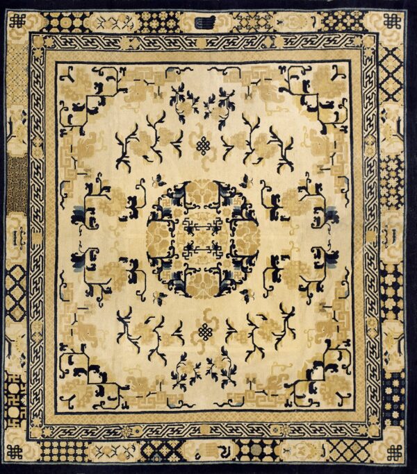 Cream rug featuring dark blue and gold stylized motifs, geometric borders, and a central round medallion design.
