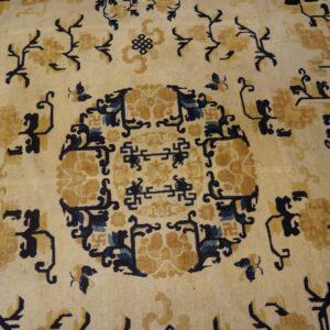 Low pile rug in cream with stylized gold and indigo floral and geometric patterns.