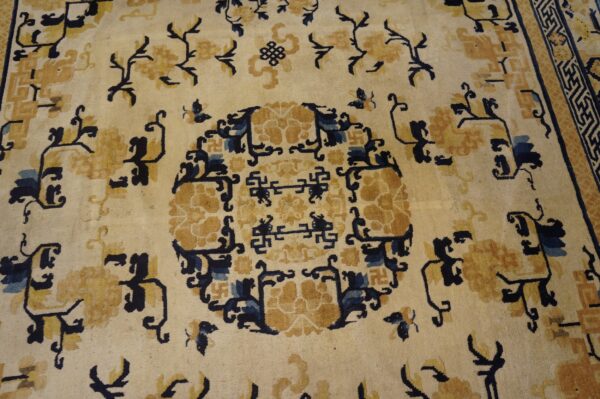 Low pile rug in cream with stylized gold and indigo floral and geometric patterns.