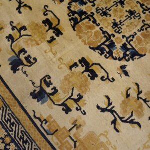 Cream and gold rug featuring stylized floral motifs, dark blue geometric accents, and a complex border design.