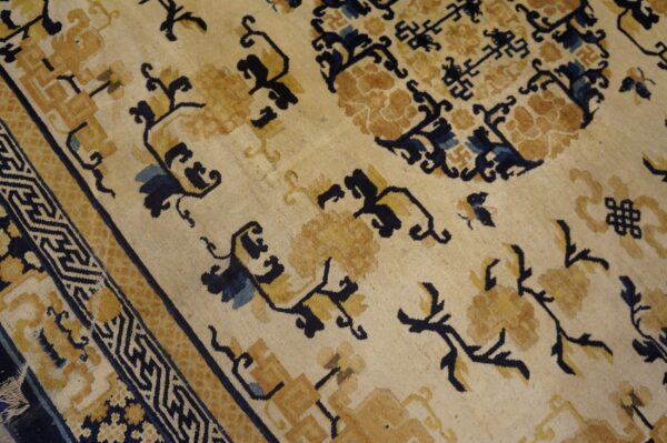 Cream and gold rug featuring stylized floral motifs, dark blue geometric accents, and a complex border design.