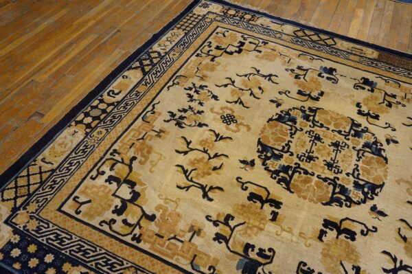 Cream and gold rug featuring dark blue floral patterns and geometric borders rests on aged wood planks.