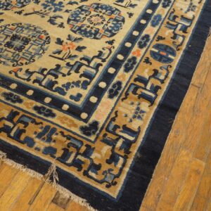 Beige, blue, and brown rug featuring geometric medallions and borders on worn yellow wood flooring.