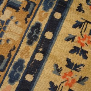 Low-pile rug detail featuring blue floral motifs, a golden field, and dark blue patterned borders.