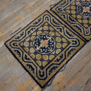 Two high-pile rugs featuring navy blue and gold geometric medallions rest on distressed wood floors.