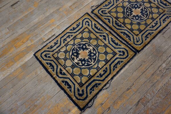 Two high-pile rugs featuring navy blue and gold geometric medallions rest on distressed wood floors.