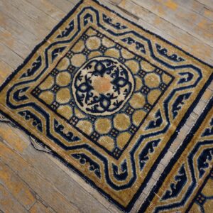 Navy and gold geometric rug fragments with peach accents rest on weathered hardwood planks.