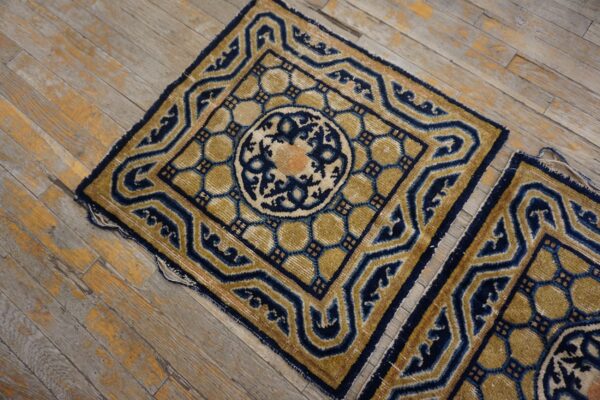Navy and gold geometric rug fragments with peach accents rest on weathered hardwood planks.