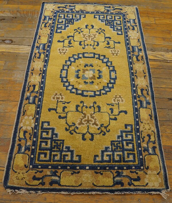 Yellow runner with indigo geometric borders and stylized floral motifs rests on worn wood planks.