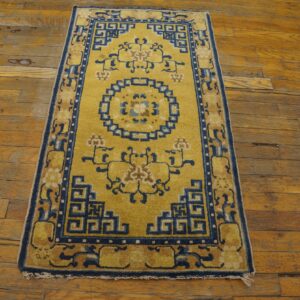 Golden yellow runner with a navy blue geometric and floral pattern lies on aged wood plank flooring.