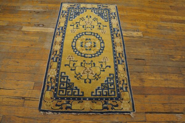 Golden yellow runner with a navy blue geometric and floral pattern lies on aged wood plank flooring.