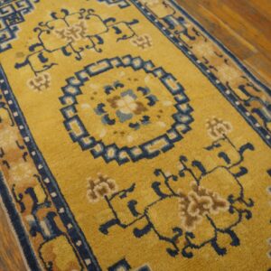 Yellow runner featuring a blue geometric center and fretwork borders on warm plank wood flooring.