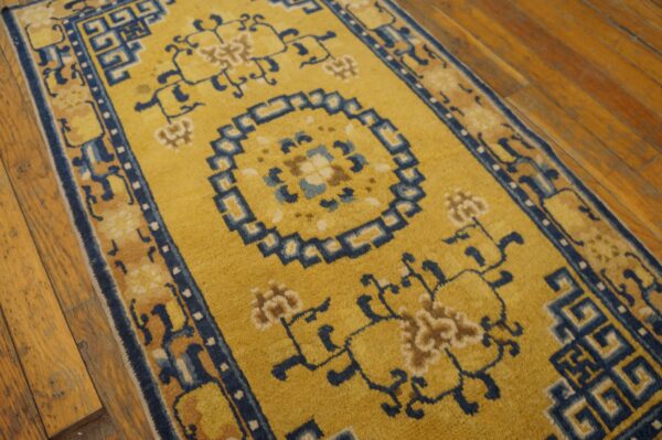 Yellow runner featuring a blue geometric center and fretwork borders on warm plank wood flooring.