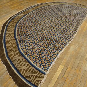Curved rug featuring blue lattice and tan fret patterns, set upon worn plank wood flooring.