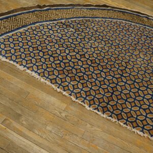 A semicircular blue and gold rug with geometric patterns and fringe rests on distressed wood floorboards.