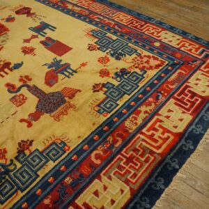 Yellow rug with red and blue symbolic motifs and complex geometric borders on rustic wooden flooring.