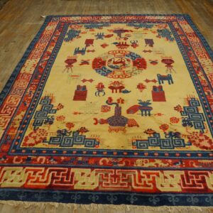 Yellow rug with detailed blue and red geometric and symbolic patterns on a wood plank floor.