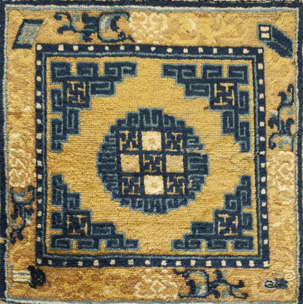 Detailed view of a gold and navy rug with a bold geometric border and central motif.