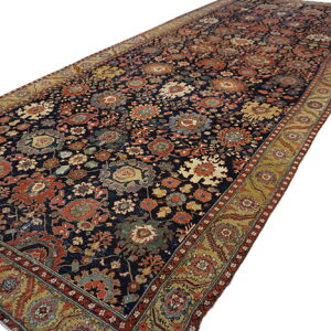 Navy blue runner rug featuring an all-over floral pattern in rust, gold, and green, with an elaborate border.