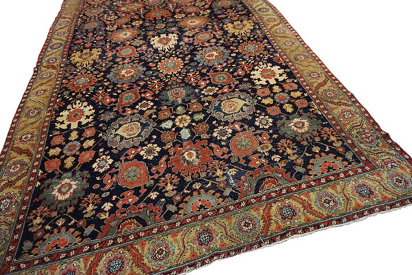 Navy blue area rug featuring dense red and gold floral motifs and a wide patterned yellow border.