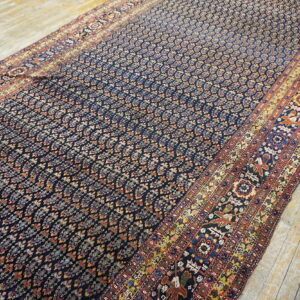Dark blue patterned runner rug with multi-colored borders lies diagonally across distressed wooden planks.