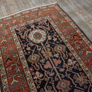 Navy and rust patterned runner rug featuring a central medallion lies on aged, gray wooden planks.