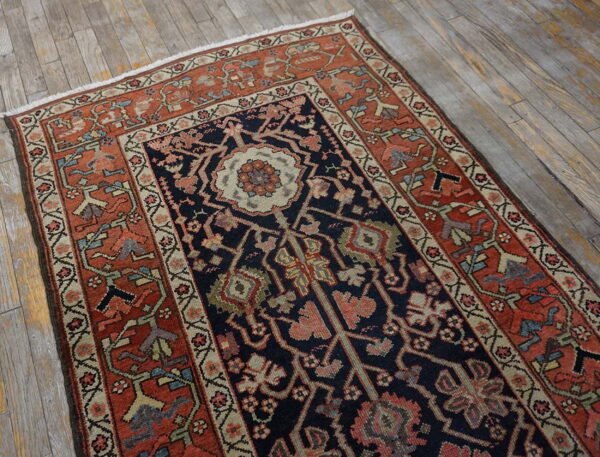Navy and rust patterned runner rug featuring a central medallion lies on aged, gray wooden planks.