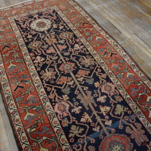 Traditional runner rug featuring a navy field, rust border, and central medallion resting on gray wood flooring.