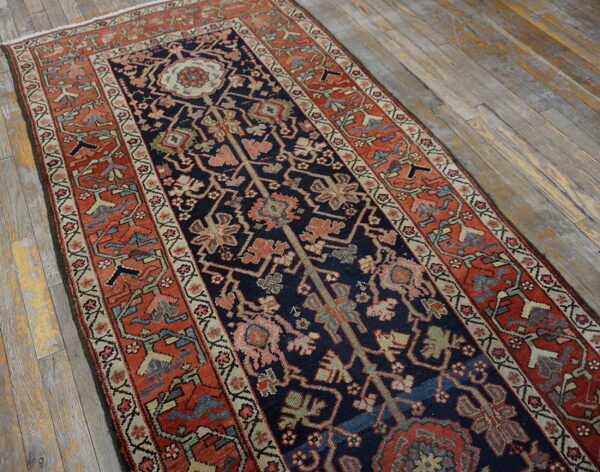 Traditional runner rug featuring a navy field, rust border, and central medallion resting on gray wood flooring.