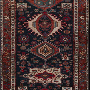 Dark blue runner rug with intricate red, cream, and teal geometric medallions and borders.